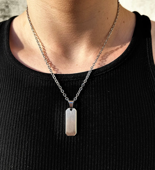 a buff guy wearing a dog tag silver pendant on a link chain in the sun