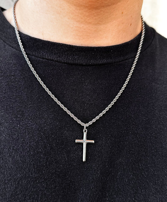 silver cross pendant on a 2mm rope chain around a models neck in natural lighting